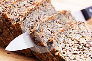 Knife in wholemeal, wholewheat bread on wooden table. Organic, healthy food