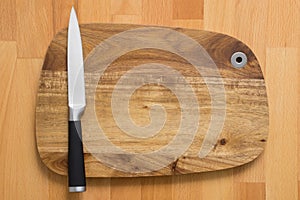 Knife on wooden cutting board on wooden background