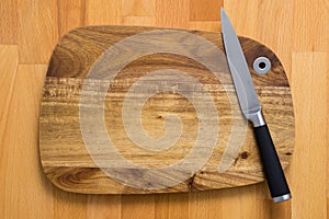 Knife on wooden cutting board on wooden background