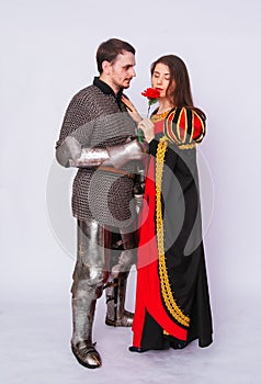 Knight in armor gives a young woman in a medieval dress a rose flower. Fantasy illustration for a book novel