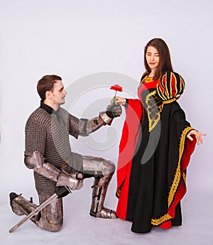 Knight in armor gives a young woman in a medieval dress a rose flower. Fantasy illustration for a book novel