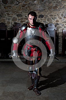 Knight in Armor With Sword Standing in Old Church and Looking at Camera