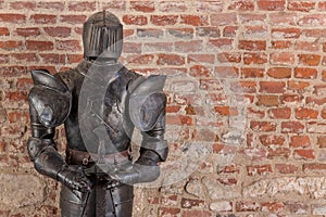 Knight armour with sword against brick wall background