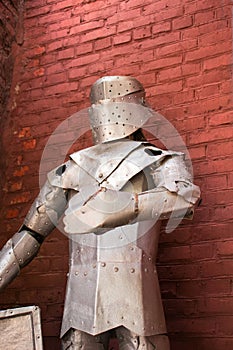 Knight`s metal armor on a red wall background.