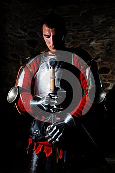 Knight Standing With Metal Sword And With Head Bowed In Prayer
