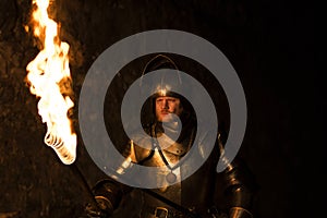 Knight with a torch and sword at night on a wall background