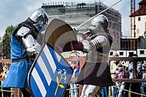 Knight tournament. The knights in the congregations are fighting in the ring. Public event in the city.