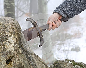 Knight tries to remove Excalibur sword in the stone