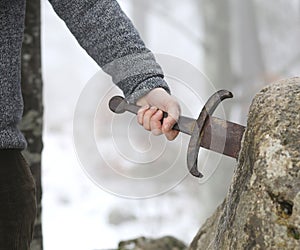 Knight tries to remove Excalibur sword in the stone