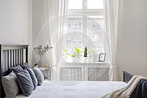 Knit blanket and pillows on bed in white hotel bedroom interior