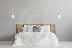 Knit blanket on wooden bed against grey wall in minimal bedroom