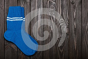 Knit blue wool socks on dark wooden background.