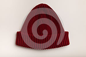 Knit burgundy colored male or unisex cap or hat on white background. Male clothing, accessories and fashion concept. Knitting