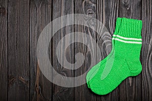 Knit green wool socks on dark wooden background.