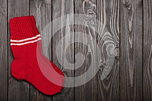 Knit red wool socks on dark wooden background.