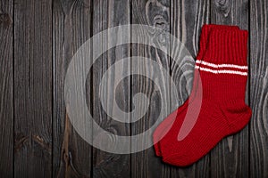 Knit red wool socks on dark wooden background.