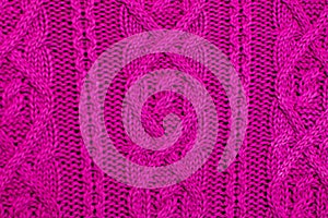 Knit texture of pink wool knitted fabric with cable pattern as background. Magenta texture