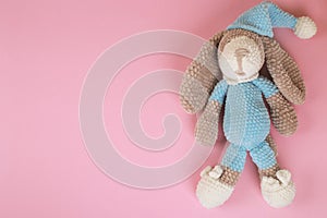 Knitted amigurumi toy doggy with space for text on a pink background