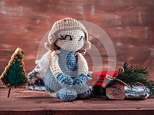 Knitted angel, amigurumi toy sits next to a jar of jam