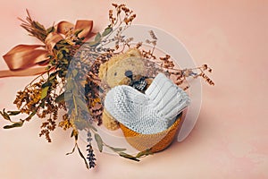 Knitted baby bootee, toy bear and flowers on soft pink background. Birth of a baby concept.