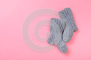 Knitted baby booties on pastel pink background