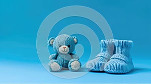 Knitted baby booties and toy bear on a blue background