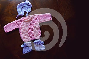 Knitted baby clothes on a dark wooden background. Baby clothes flat lay closeup