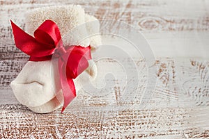 Knitted baby socks with red bow on the wooden surface