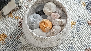 A knitted basket holds various balls of yarn, including colors like gray, beige, peach, and a standout mustard yellow photo