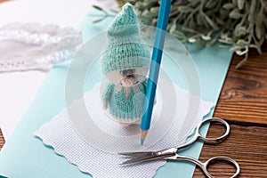 A knitted blue dwarf holds a pencil. Handmade,