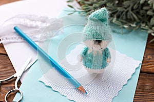 A knitted blue dwarf holds a pencil. Handmade,