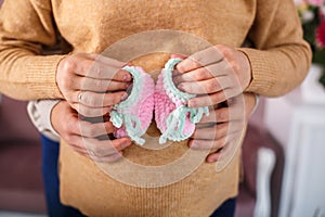 Knitted booties in the hands of a pregnant woman next to her husband. waiting for a miracle