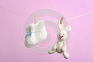Knitted booties and toy bunny hanging on washing line. Baby accessories