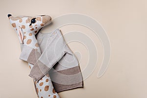 Knitted brown, beige sweater and giraffe soft toy. Set of baby stuff and accessories for newborn on pastel background