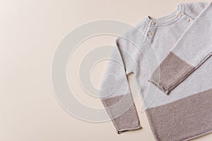 Knitted brown and beige sweater. Set of baby stuff and accessories for newborn on pastel background. Baby shower or baby