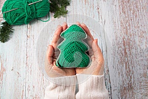 Knitted Christmas tree in woman hands. Close-up. Handmade Christmas gifts