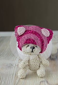 Knitted crochet small pink hat on sad bear. Women`s hat for feminists march protest. Creative craft work