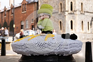 Knitted and crocheted doll depicting Queen Elizabeth, draped over a mailbox