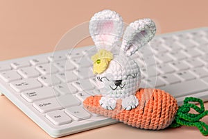 . Knitted Easter bunny on a blue background with a keyboard. Happy easter. Blank for Easter greetings for people whose profession