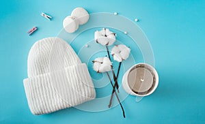 Knitted hat, cotton sprigs, macaroons close-up on a white