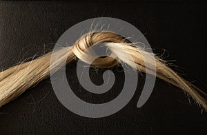 Knitted in a knot of female blond hair on a black background
