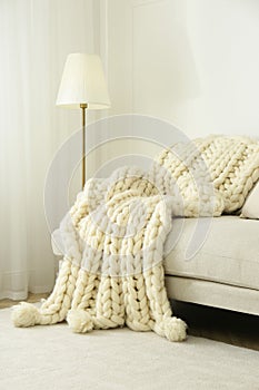 Knitted merino wool plaid on sofa in room