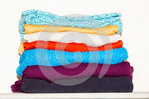 The knitted multi-colored jumpers are not very even stack. Red, blue, bard, white, yellow carpet. Behind the white background