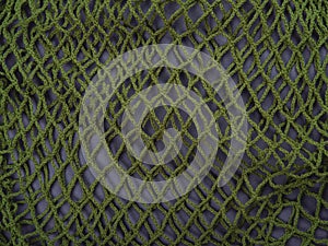 The knitted net background of one green zero waste string bag, closeup. Selective focus