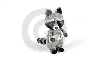 knitted raccoon with fish in hands on white background