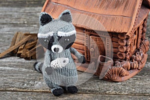 knitted raccoon with a fish in his hands on a wooden table