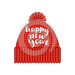 A knitted red cap with a pompom with the inscription `Happy new year`. Isolated on a white background. Autumn or winter seasonal a