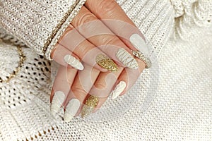 Knitted sand manicure on long oval nails with golden sequins and threads