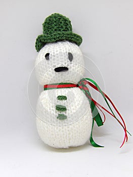 Knitted snowman child`s toy with green hat and ribbon scarf isolated on white background