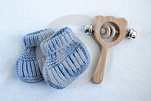 Knitted socks for newborns and wooden baby toy on white background. Concept of handmade knitted clothes and toys for babies.